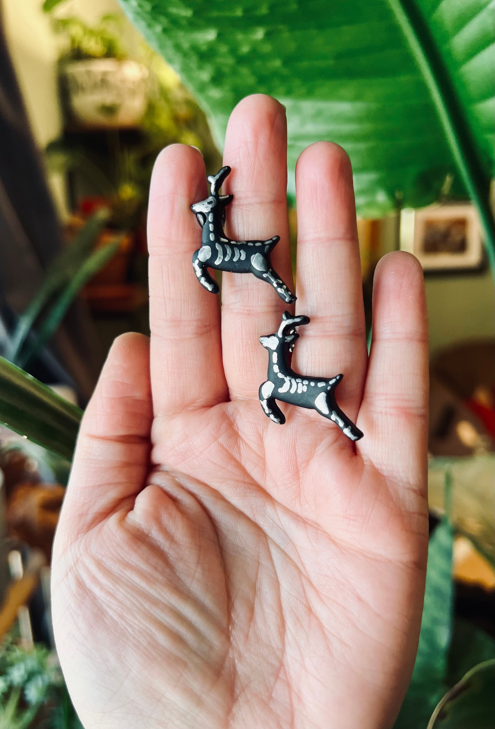 Summon a touch of gothic elegance with our black reindeer skeleton earrings, adorned with silver bones for a hauntingly beautiful accessory.