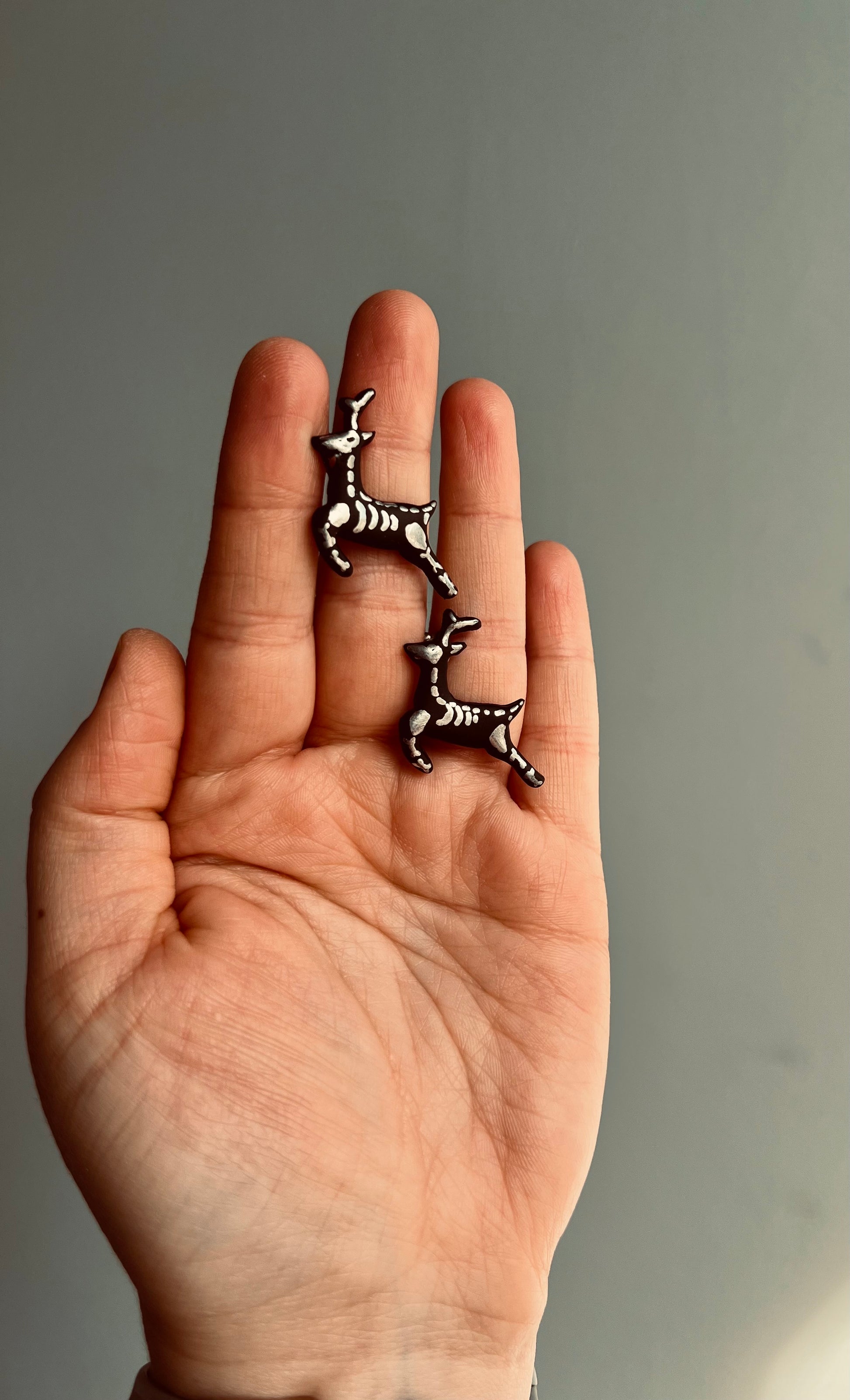 Enhance your style with our gothic reindeer skeleton earrings, featuring silver bones against a striking black backdrop for a bold statement.