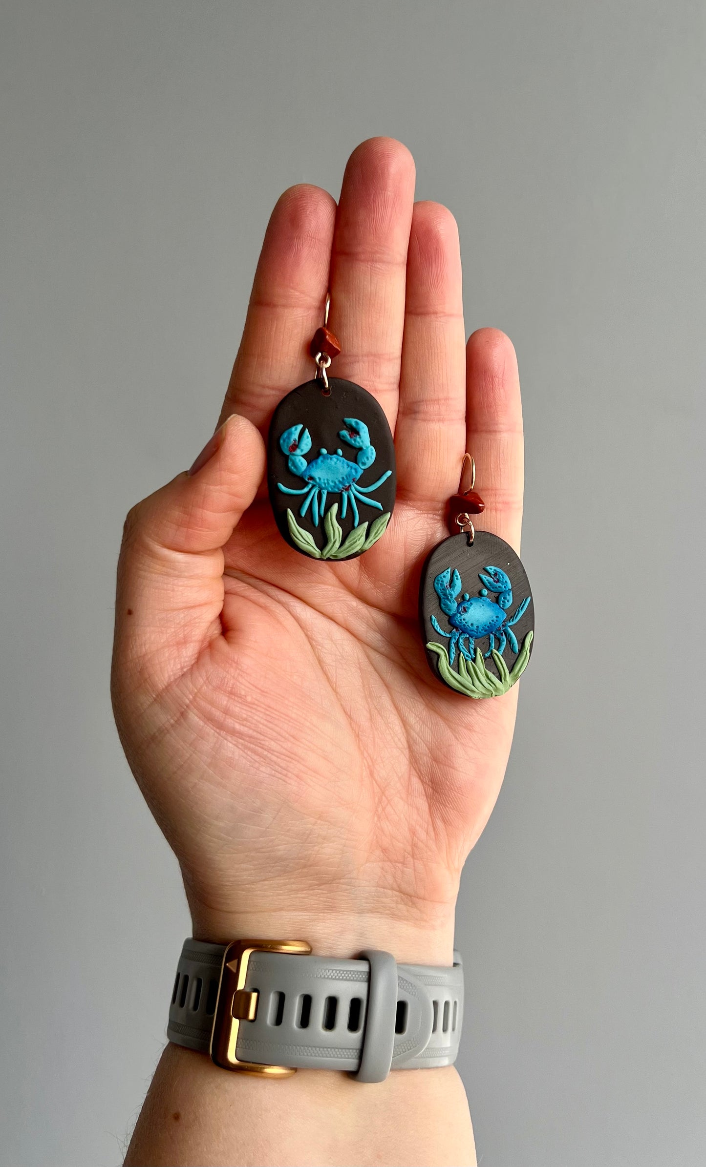 Unique polymer clay Cancer zodiac earrings adorned with red jasper, portraying a blue crab in its oceanic habitat. Handcrafted with care, these earrings capture the intuitive and nurturing essence of Cancer, while the red jasper accent enhances emotional balance. Embrace your sensitivity with this symbolic accessory. Shop now!