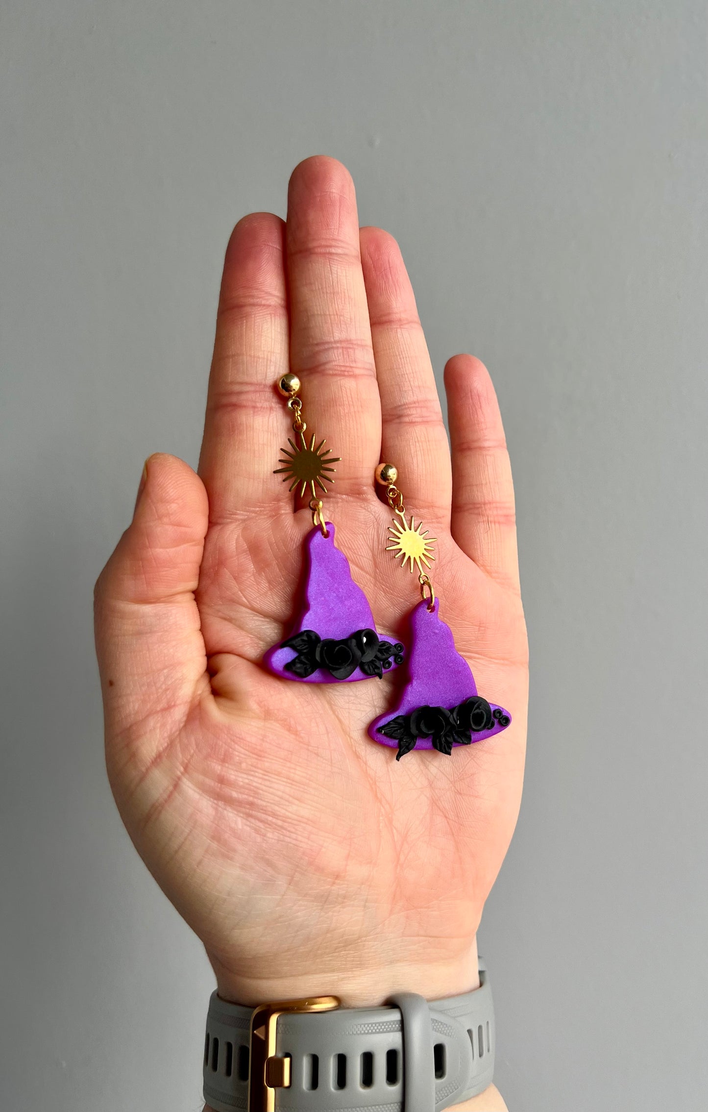 Embrace enchantment with our purple witch hat earrings, featuring black rose embellishments and a sun charm. Symbolizing wisdom and intuition, these earrings capture the mystique of witch hat folklore