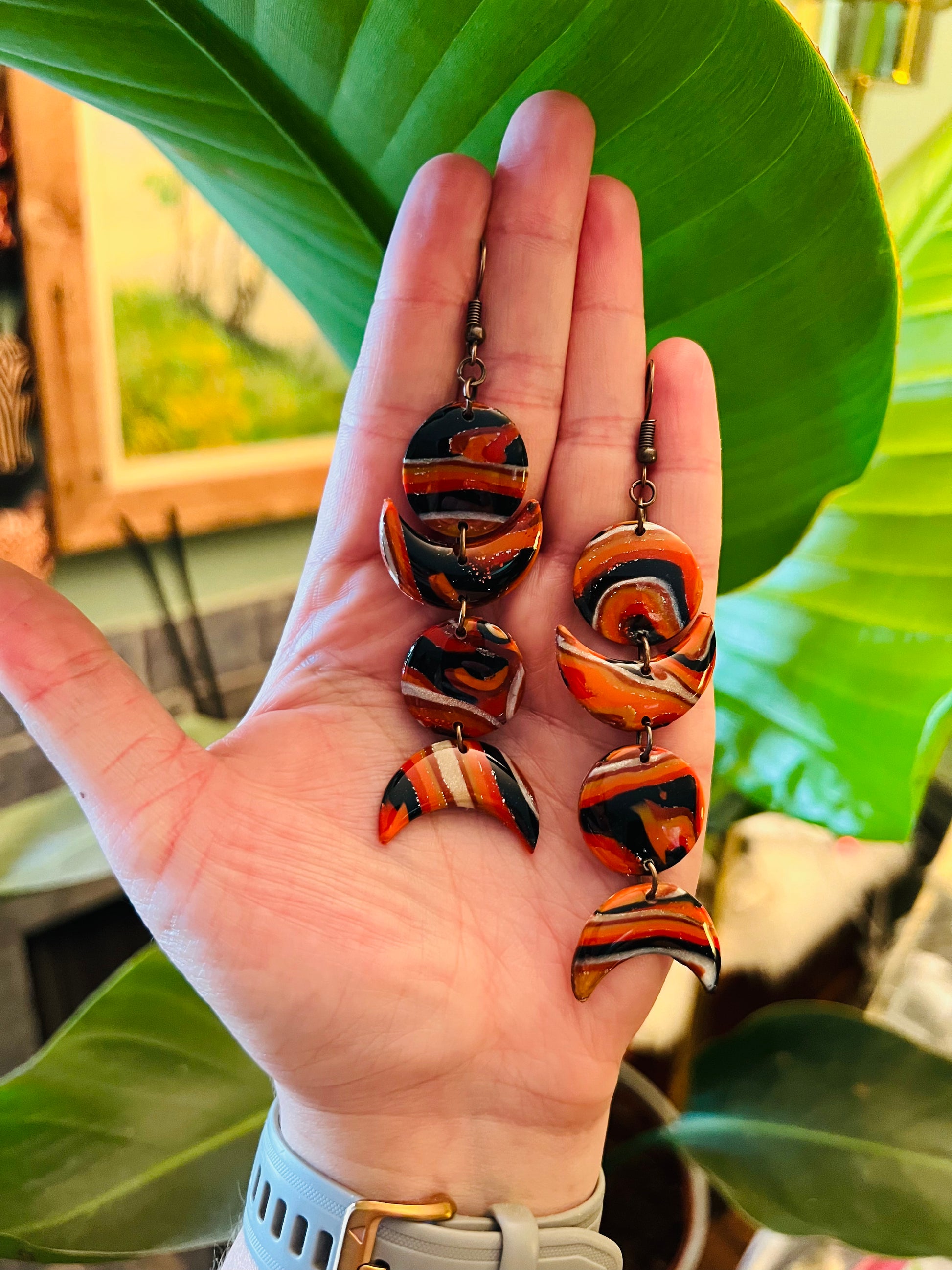 Elevate your style with our unique red, black, and orange marbled polymer clay earrings, meticulously crafted in the shape of the moon phases. Each pair exudes celestial charm and artisanal beauty, perfect for adding a touch of cosmic elegance to any outfit. Embrace the enchantment of the lunar cycle with these statement earrings!